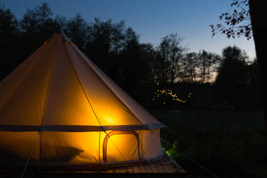 Glamping bell tent glows at night at forest